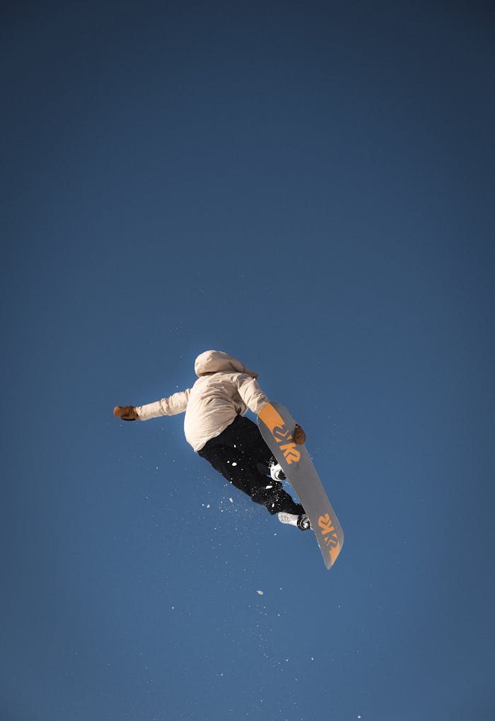 Mastering the First Impression: Your intriguing post title goes here A snowboarder performs an aerial trick against a clear blue sky in Le Grand-Bornand, France.